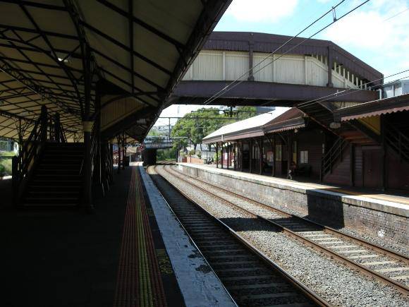 Looking northwards along the edge of Platform 2 with the south elevation of the roofed footbridge between the Platforms visible at upper right
