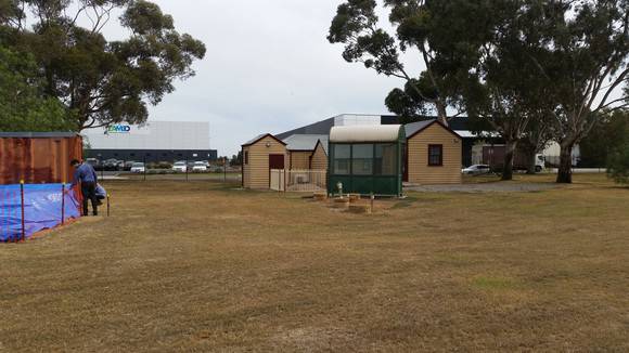 Context showing Harricks Cottage with the demounted prefabricated building under the tarpaulin May 2018